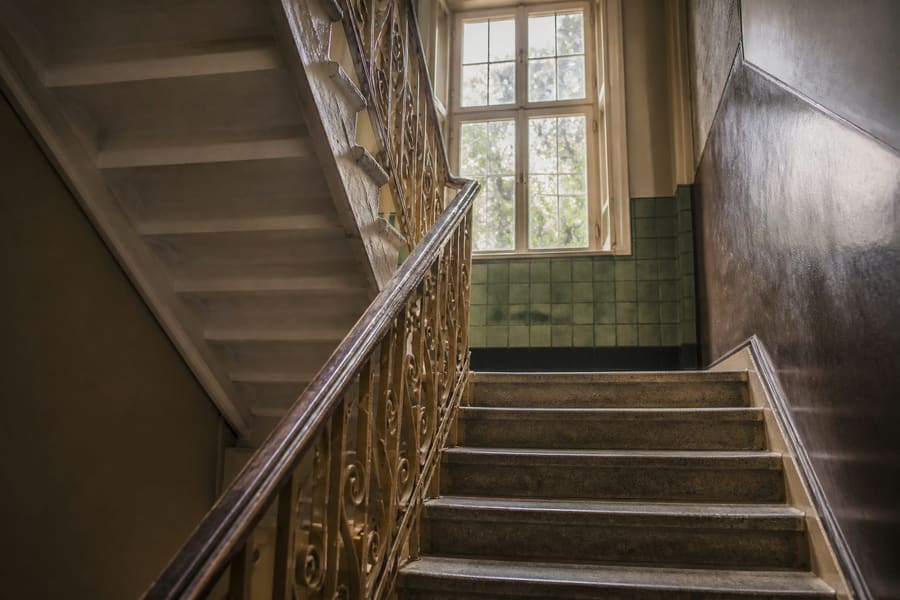 The common staircase of a prewar walk-up, worn treads and a painted metal banister