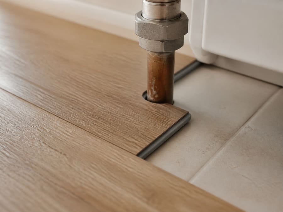 A vinyl plank cut neatly around a radiator pipe on a bathroom floor